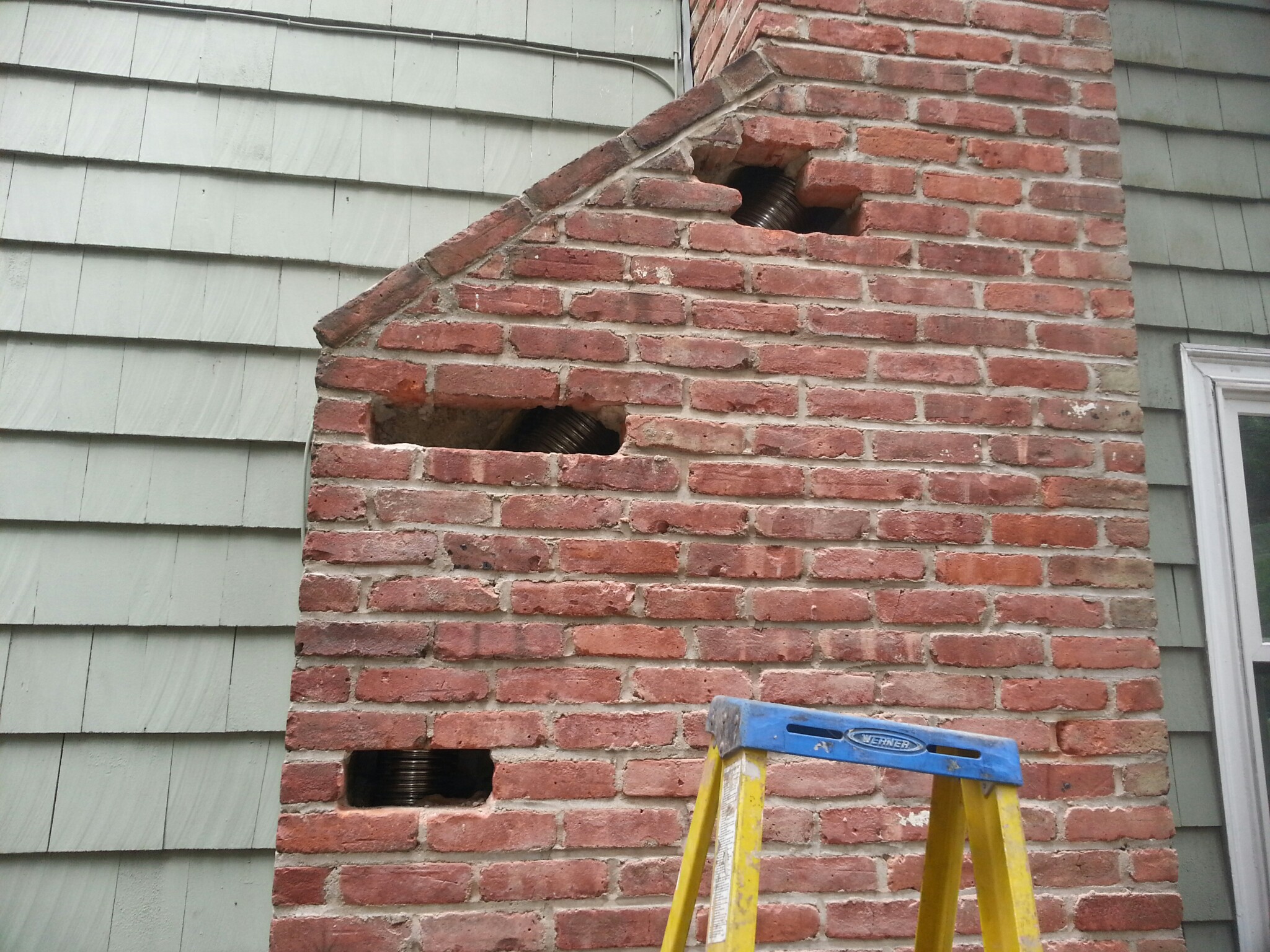 A NEW STAINLESS STEEL CHIMNEY LINER BEING LOWERED INTO THE CHIMNEY FLUE IN MONTAUK